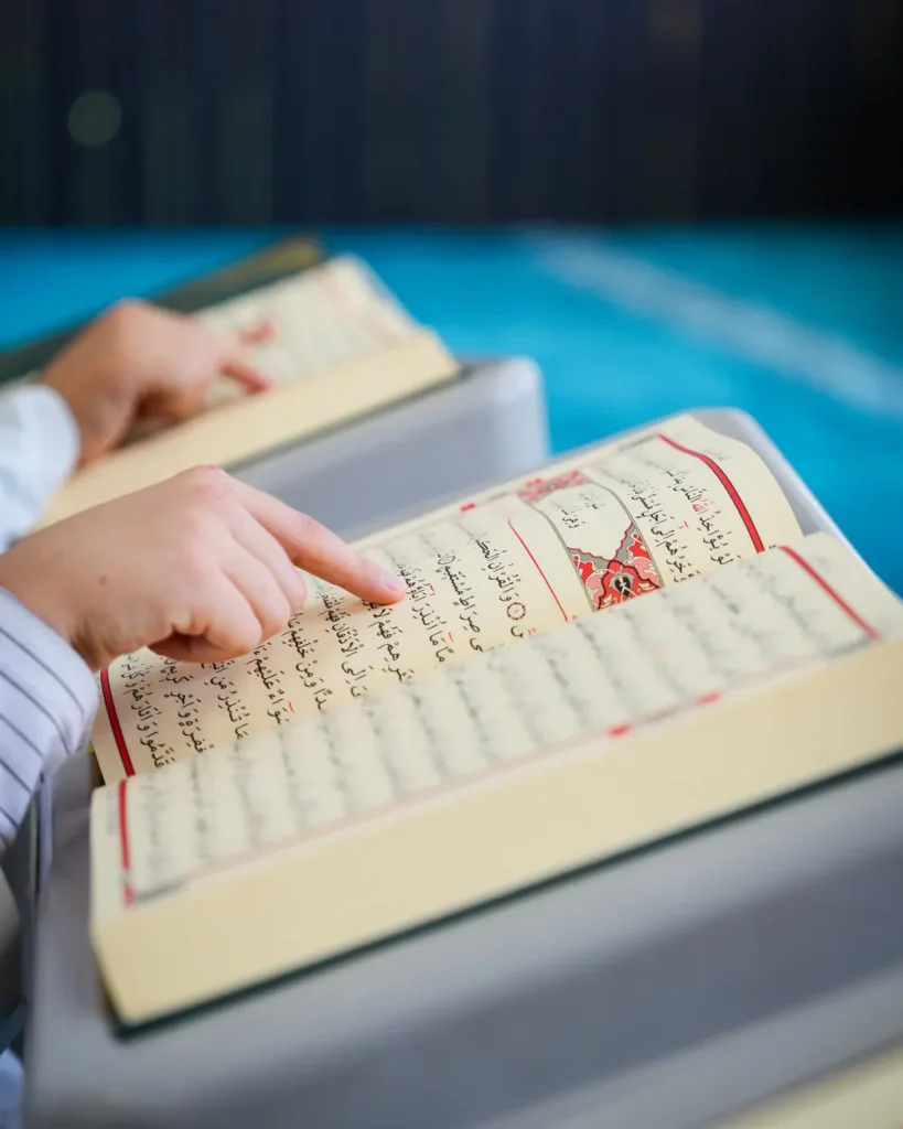 Child following the words with a finger while reading the Quran